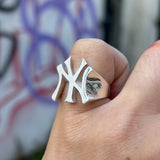 A silver-toned New York Yankees interlocking logo ring worn on a person's finger.
